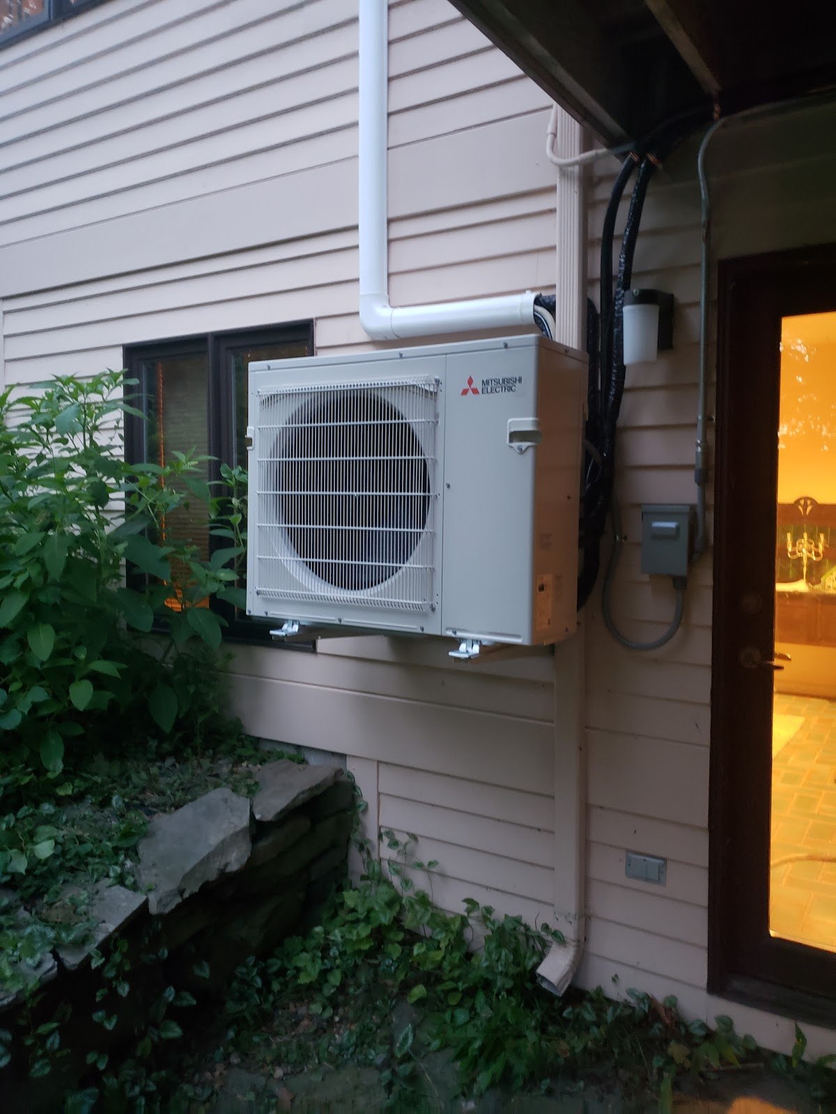 Mitsubishi ductless condenser wall-mounted outside a home by Pro Air Care HVAC